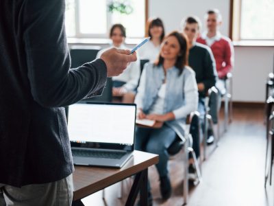 Everyone is smiling and listens. Group of people at business conference in modern classroom at daytime Everyone is smiling and listens. Group of people at business conference in modern classroom at daytime.