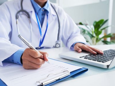 Filling document Doctor checking information in computer program before filling medical card